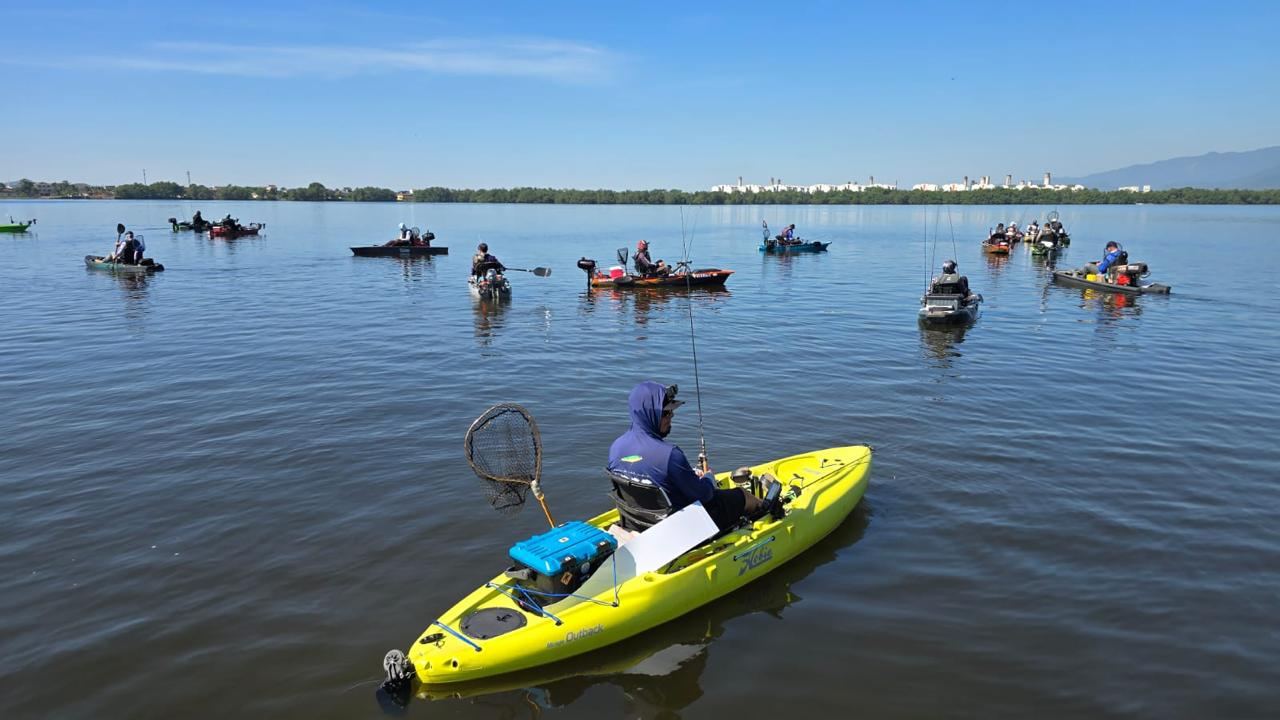 Caiaques na raia de pesca, com pescador em caiaque amarelo em primeiro plano